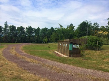 The gravel track curving past a small timber building